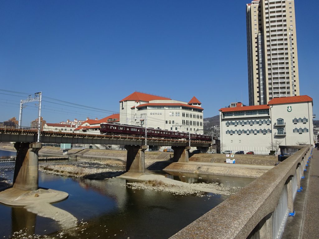 宝塚大劇場をバックに鉄橋を渡る阪急今津線電車